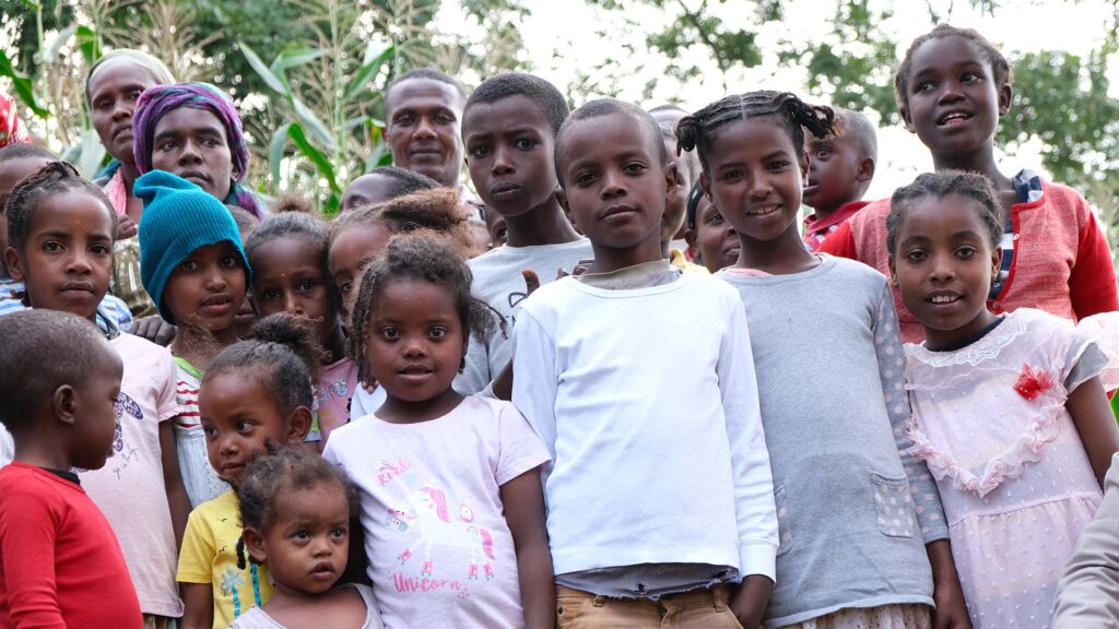 a group of children smile or look curiously at the camera